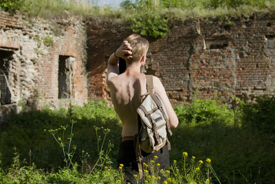 Rear view of young boy in field by brick wall