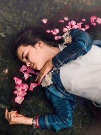 High angle view of woman with rose petals on hair lying over grass 
