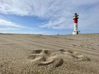 Lighthouse on beach against sky