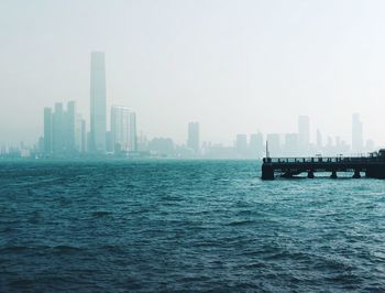 Sea by buildings in city against sky