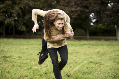 Young man carrying woman on shoulder at park