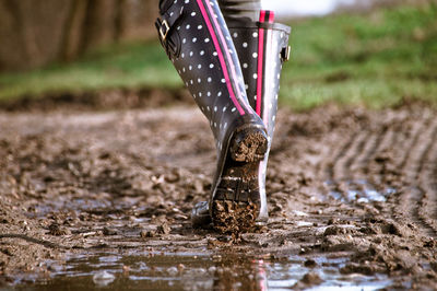 Low section of woman with umbrella in puddle