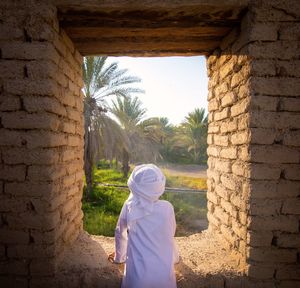 Rear view of woman standing against brick wall