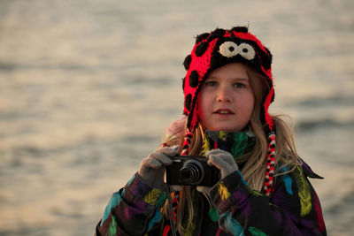 A 9 year old girl practices her photography and camera skills at the beach in the evening