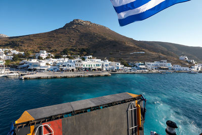 Buildings by sea against clear blue sky