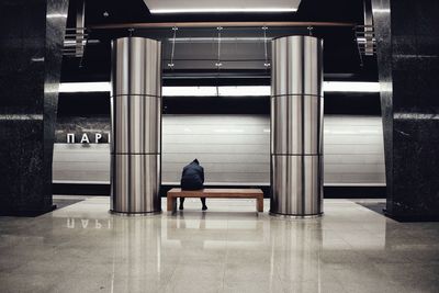 Rear view of man sitting on bench at subway station