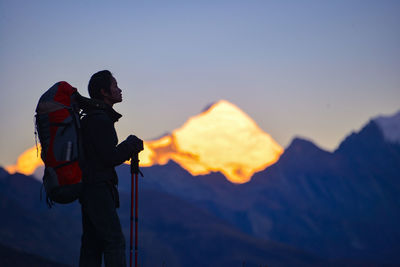 Side view of hiker standing against mountain