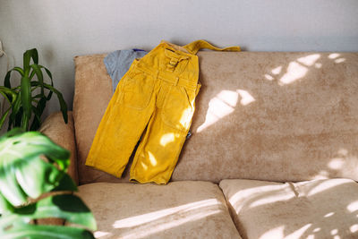 Children's clothing yellow jumpsuit and t-shirt lie on the sofa.