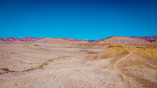 Scenic view of desert against clear blue sky