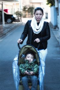 Portrait of mother pushing baby carriage on street