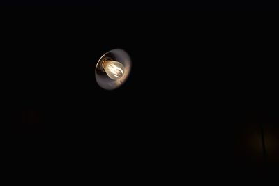 Low angle view of illuminated lamp against black background