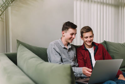 Young man using mobile phone while sitting on sofa