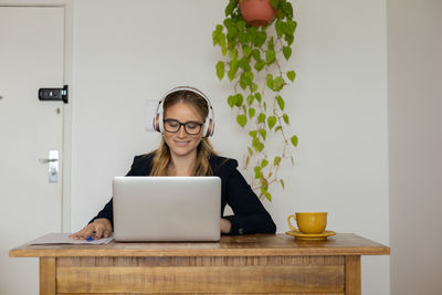 Woman working at home with laptop and papers on desk and headphones. home office . gray notebook 