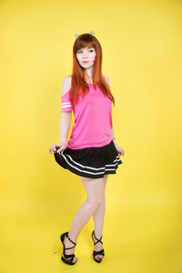 Portrait of a young woman against yellow background