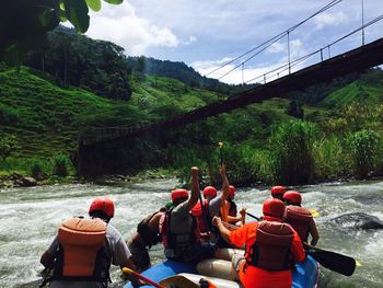 Rear view of men rafting in river