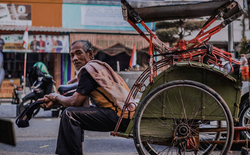 Side view of senior man sitting in jinrikisha on street