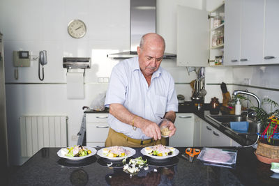 Senior man preparing salad in the kitchen