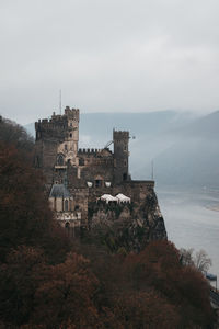 Built structure by river against sky