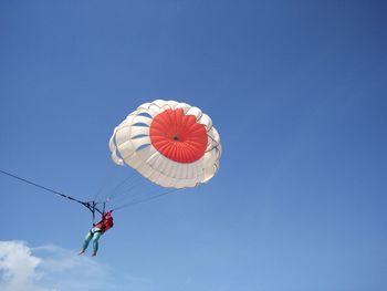 Low angle view of person parasailing against blue sky