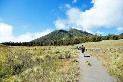 Rear view of people walking on mountain against sky