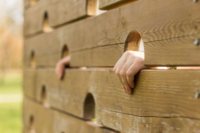 Midsection of person with umbrella on wood against wall