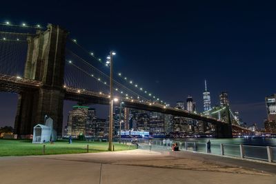 Illuminated bridge over river in city at night