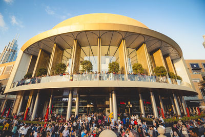 People at shopping mall against sky in city