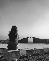 Rear view of woman looking at camera against sky