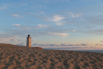 Lighthouse by sea against sky