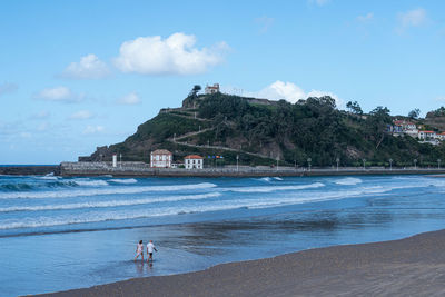 People on beach by sea against sky