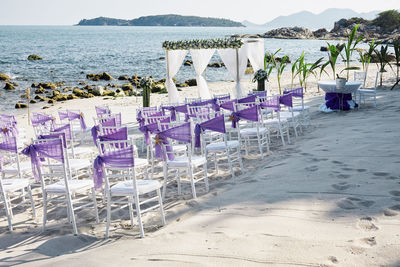 Chairs on beach by sea against sky