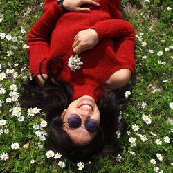 High angle portrait of woman wearing sunglasses lying on land