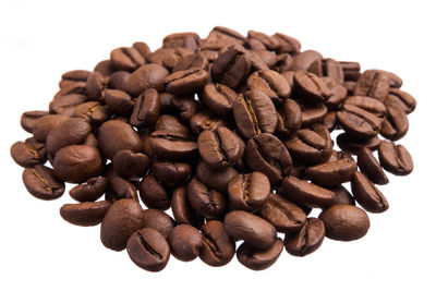 Close-up of roasted coffee beans against white background