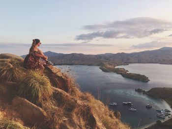 Man standing by lake against sky during sunset