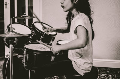 Midsection of girl playing drum at home