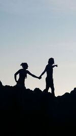 Silhouette man and woman standing against clear sky