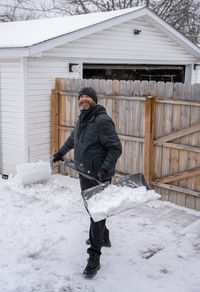 Man is using a snow shovel to clear your sidewalk and driveway after a recent snow storm