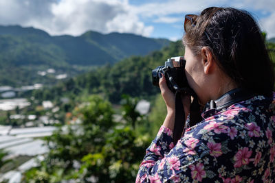 Close-up of woman photographing against sky