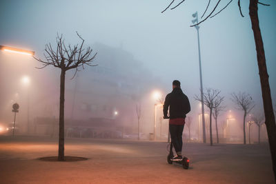 Wide shot of man on electric scooter on a foggy day