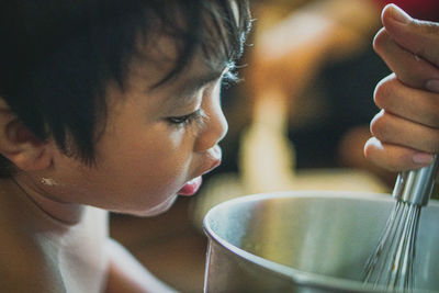 Baby boy looking at cropped hand preparing food