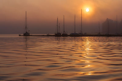 Sailboats sailing on sea against sky during sunset