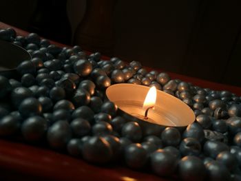 Close-up of illuminated tea light candle amidst pebbles