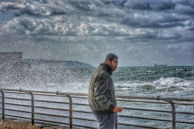 water, sea, sky, railing, lifestyles, cloud - sky, horizon over water, standing, leisure activity, nature, scenics, beauty in nature, rear view, tranquility, waist up, wave, casual clothing, tranquil scene