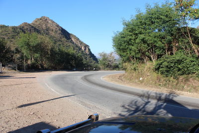 Road amidst trees against clear sky