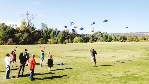 People playing soccer on field against sky