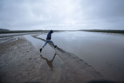 Side view of man on beach against sky