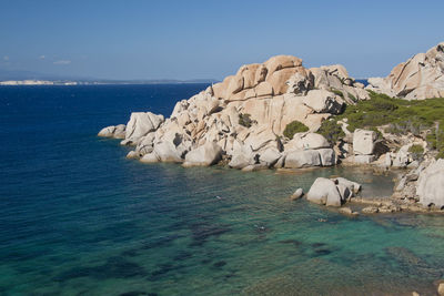 Rock formations by sea against blue sky