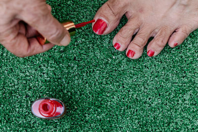 Old man painting his wife's toenails red seen from above