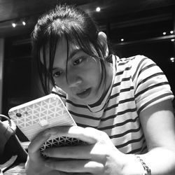 Close-up of young woman using phone while sitting at table