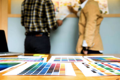 Midsection of colleagues analyzing color swatch in office